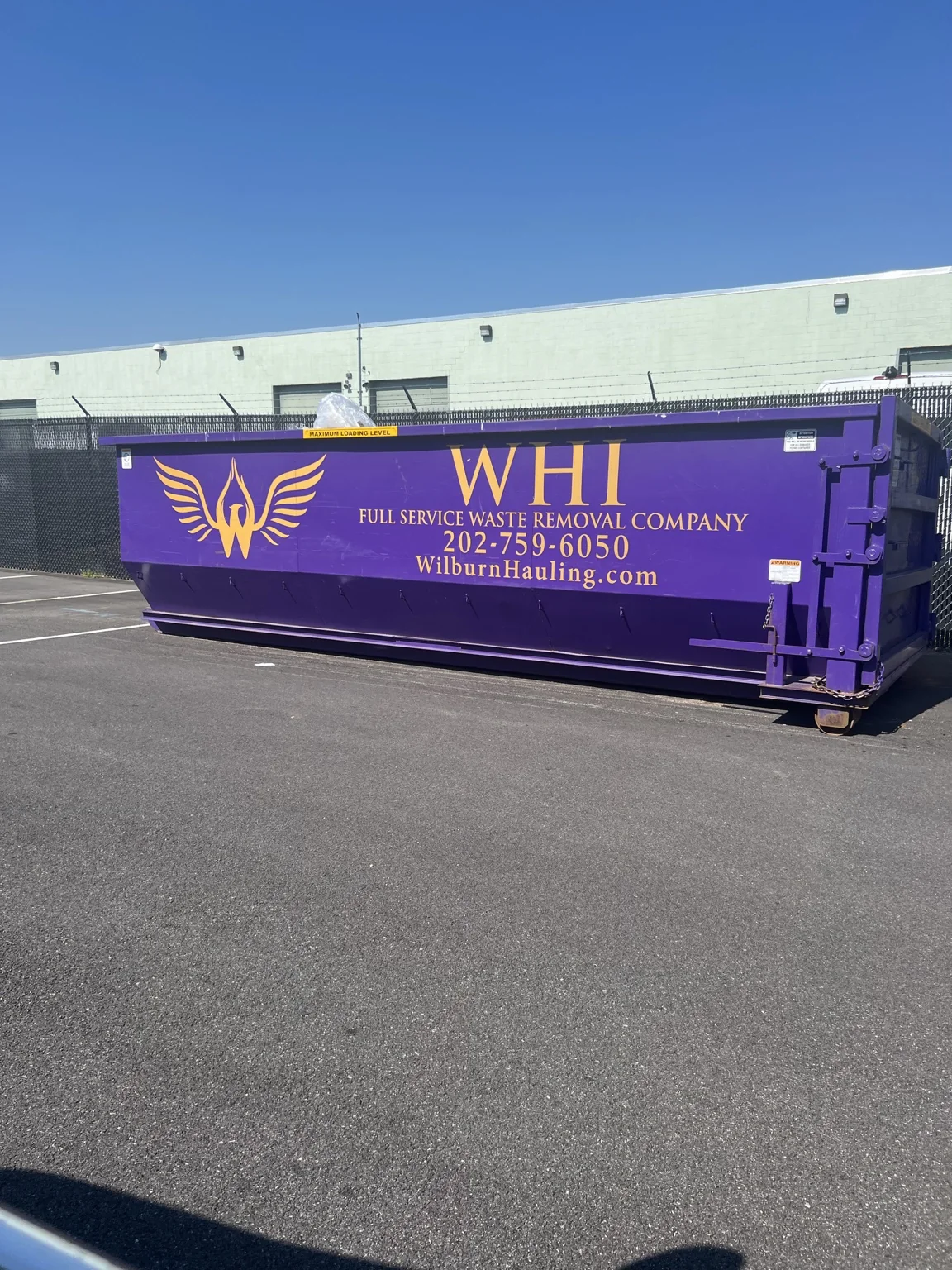Purple Wilburn Hauling roll-off container with gold company branding